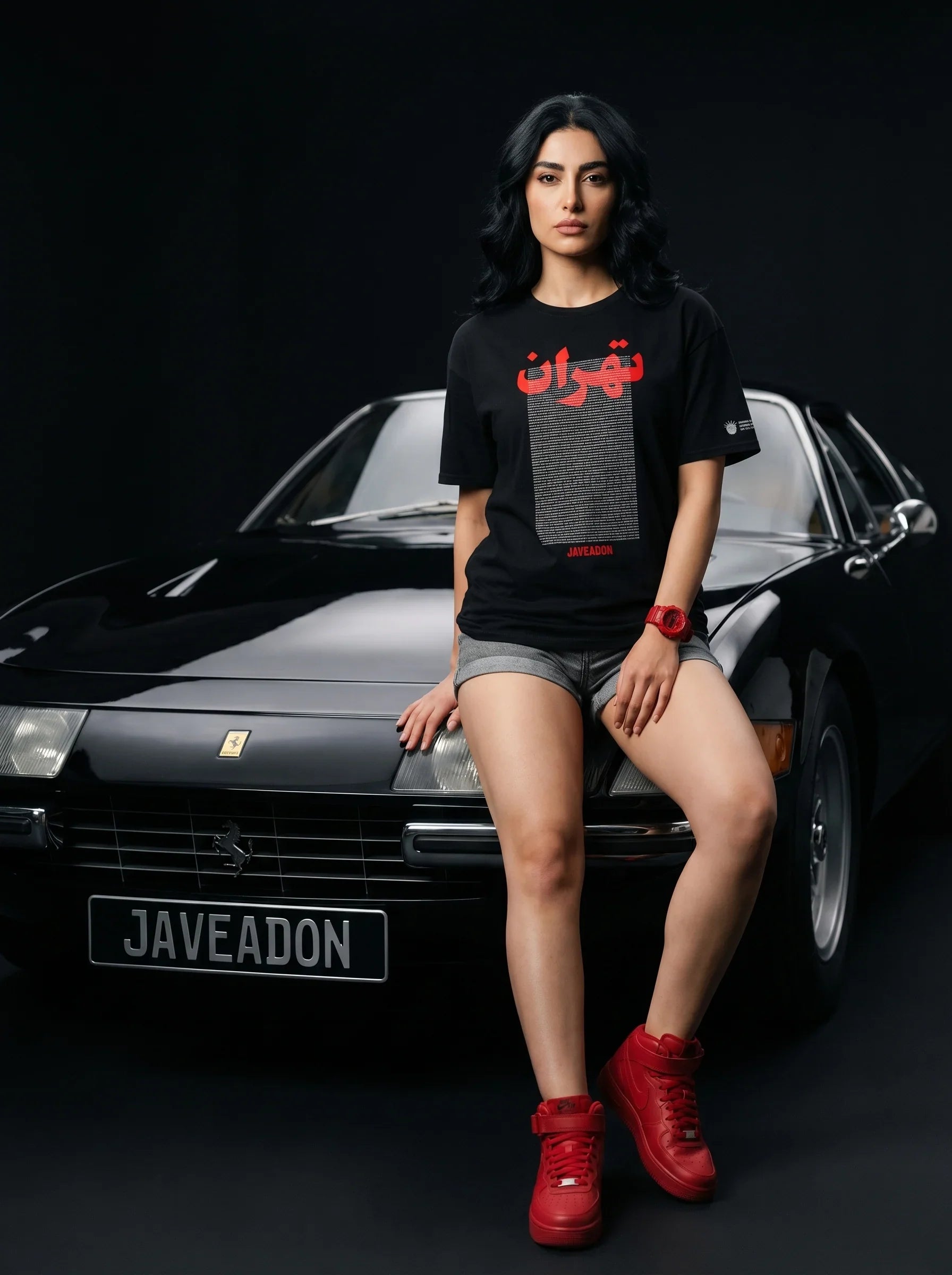 Woman in black Persian graphic tee with red sneakers, sitting on classic car, bold streetwear style