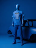 Blue mannequin wearing Persian-inspired streetwear tee with text graphic, styled with joggers and sneakers beside vintage car