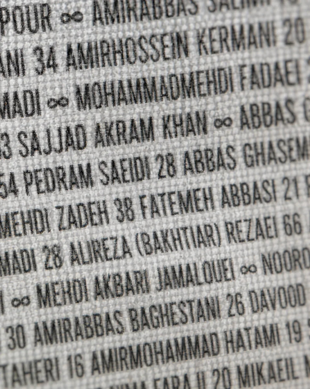 Textured fabric with printed Persian names and numbers, evoking heritage and identity.