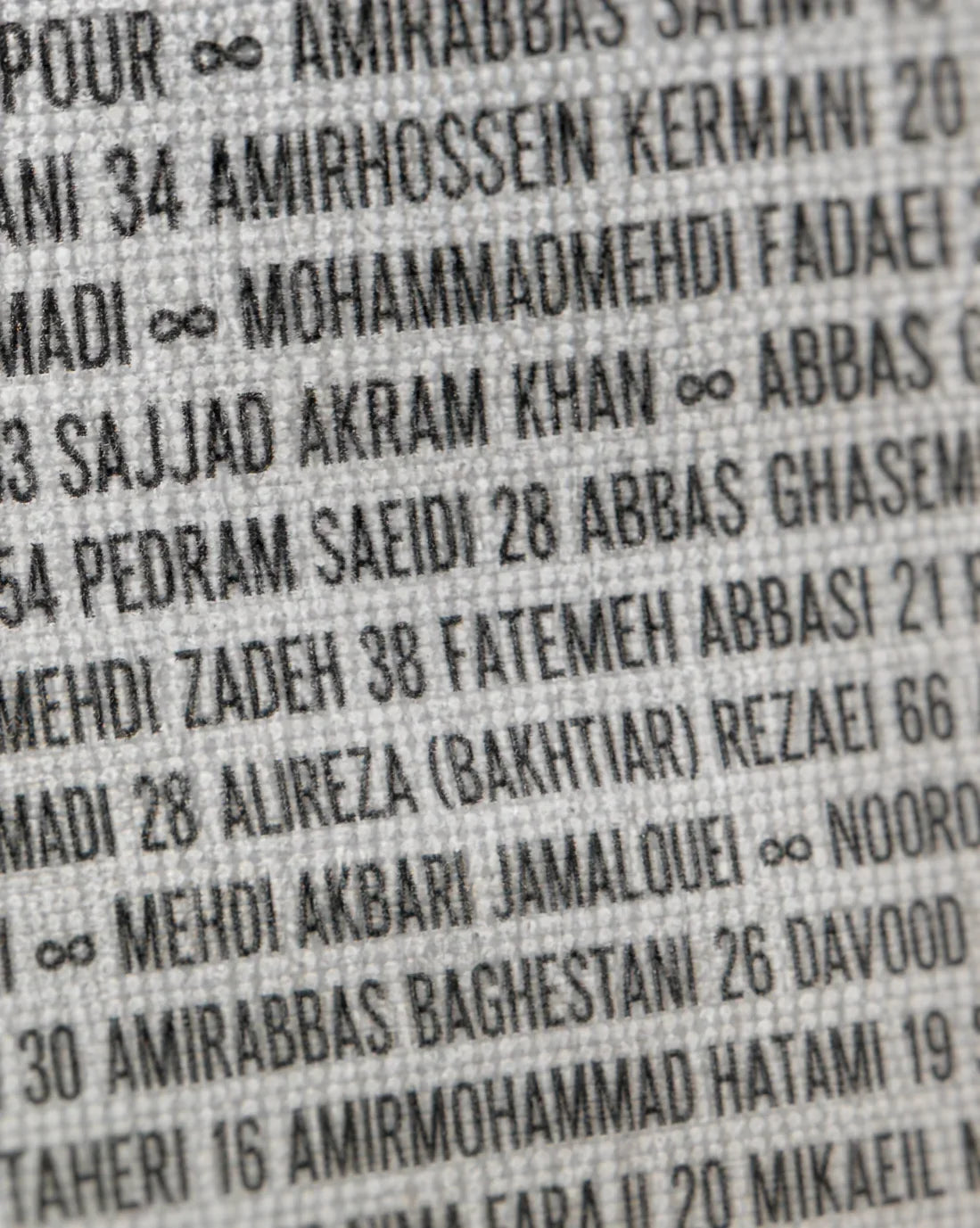 Textured fabric with printed Persian names and numbers, evoking heritage and identity.