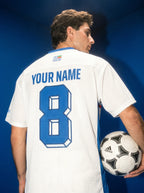 White soccer jersey with blue number 8 and 'YOUR NAME', held with Adidas ball, Persian heritage design