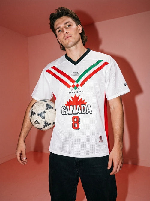 Man holding soccer ball wearing white jersey with 'Iranians for Canada' and red maple leaf design