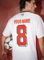 Custom white soccer jersey with red number 8, personalized name, and Persian-inspired emblem, held with Adidas ball.